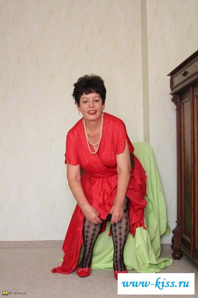 Раздетая старушка подняла длинное платье у комода 