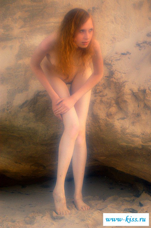 Раздетая красавица сидит боком на природе