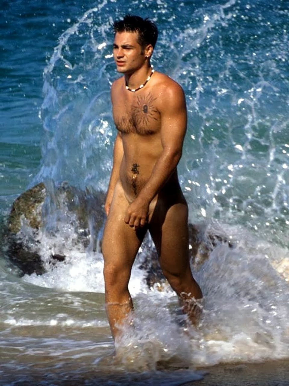 Мускулистый голый парень на пляже