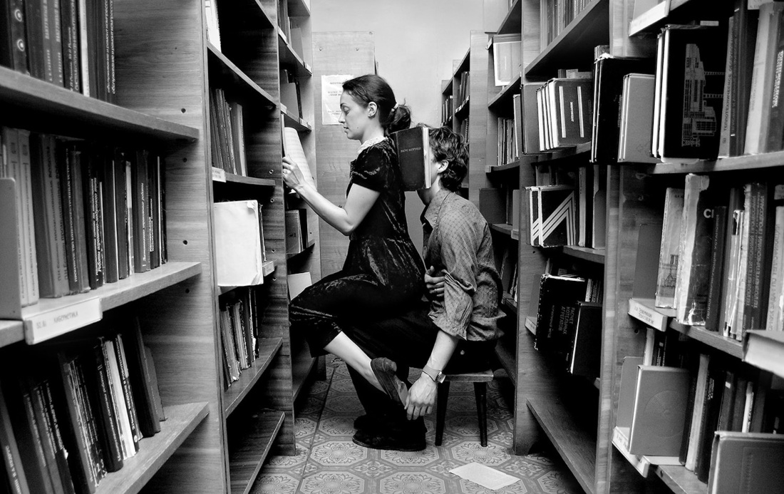 Женщина звонит около книжной полки